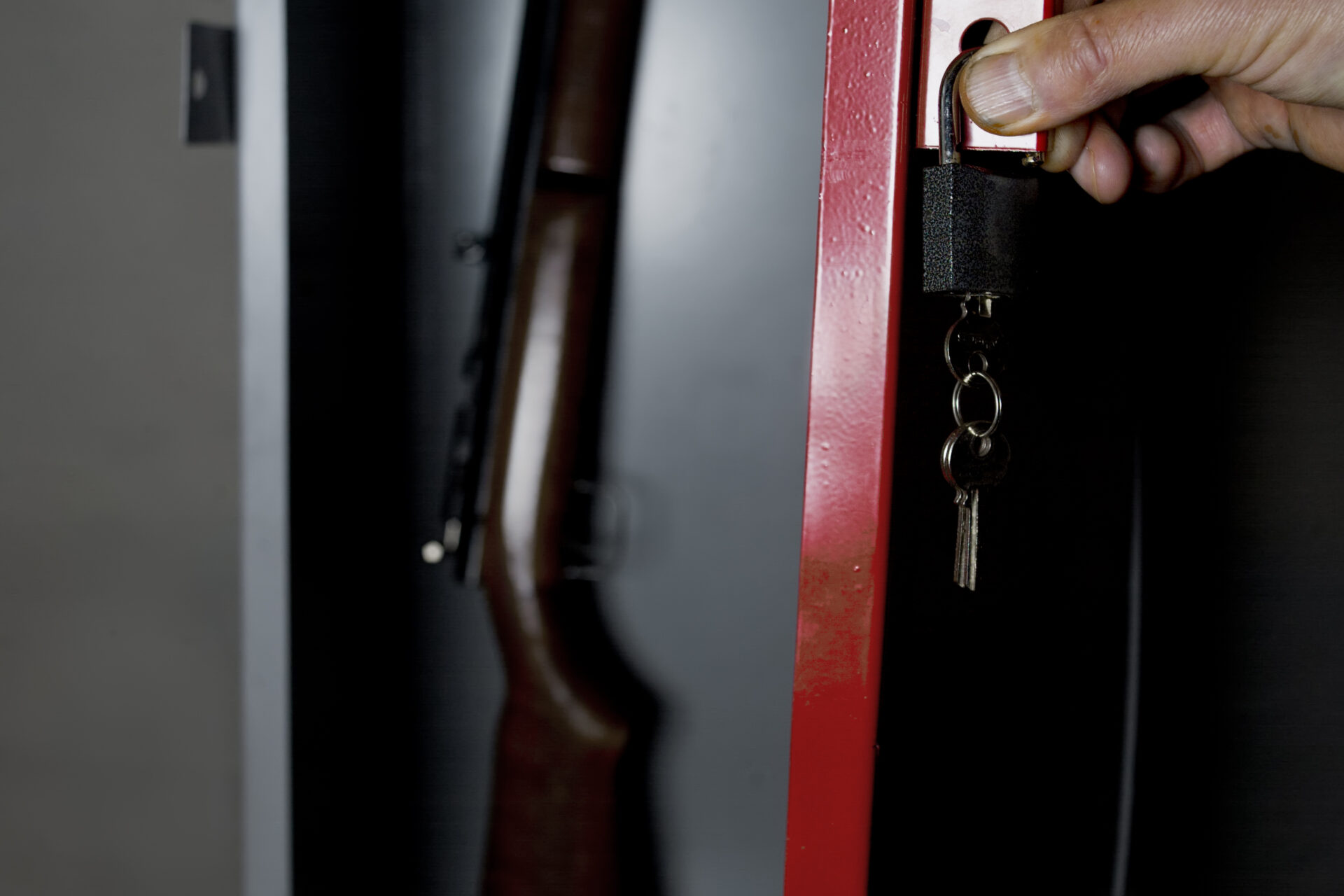 Human hand opening a metal safe with a gun inside, studio cropped shot.