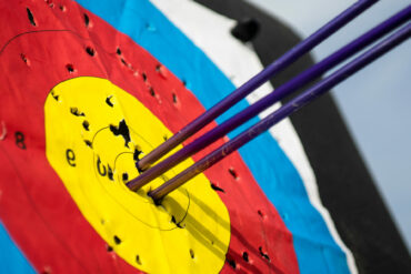 Close up on three arrows in the middle center of the target goal achieved success archery.